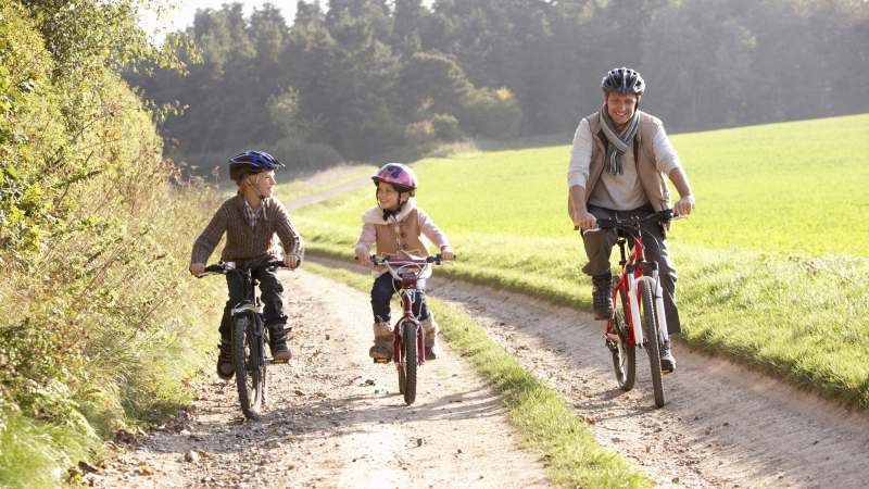 En familj cyklar längs en grusväg.